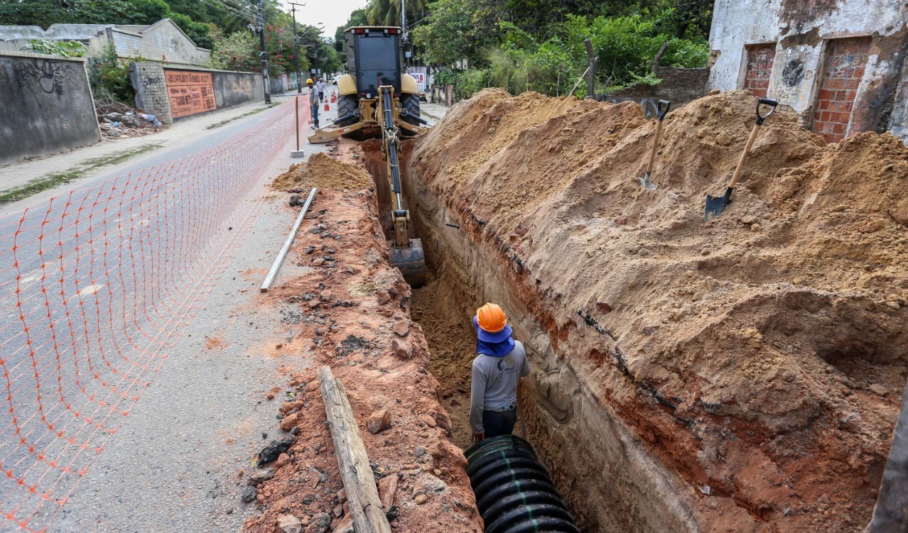 a foto mostra operários trabalhando numa obra de drenagem, eles estão instalando uma tubulação na via